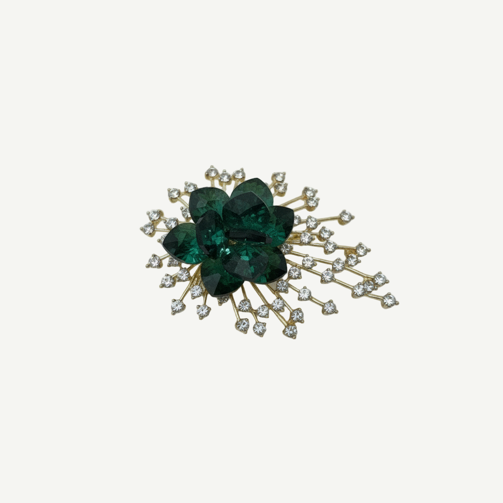 Broche Esmeralda Radiant Swarovski con cristales verdes y microcristales blancos, estructura dorada tipo explosión radial. Elegante, llamativo y perfecto para eventos especiales.