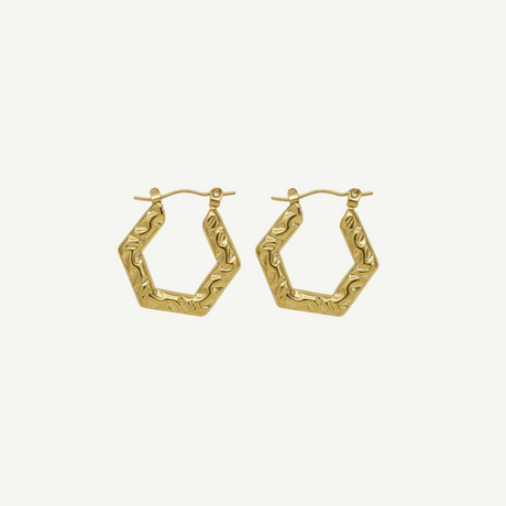 Pendientes Atenea hexagonales texturizados en latón con baño de oro, ligeros y elegantes para looks modernos y sofisticados.